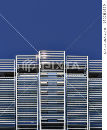Modern building facade with blue metal louvers against a clear sky Modern building facade with blue metal louvers against a clear sky 140261439
