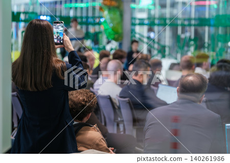 Woman recording business conference audience with smartphone in modern office meeting room during presentation Woman recording business conference audience with smartphone in modern office meeting room during presentation 140261986