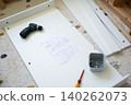 Tools and assembly instructions on white furniture panel with screws and drill on carpeted floor 140262073