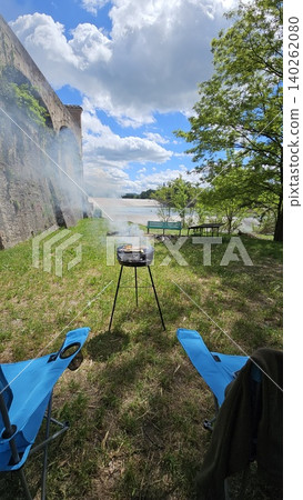 Folding chairs next to barbecue on a sunny day at a picnic by the river Folding chairs next to barbecue on a sunny day at a picnic by the river 140262080