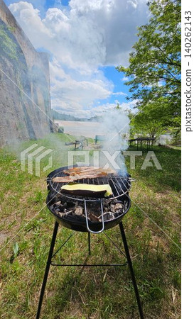 Vertical Image of barbecue smoking on a sunny day at a picnic by the river Vertical Image of barbecue smoking on a sunny day at a picnic by the river 140262143