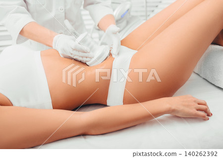 Beautiful woman having cavitation , cellulite treatment, on her belly at beauty clinic Beautiful woman having cavitation , cellulite treatment, on her belly at beauty clinic 140262392