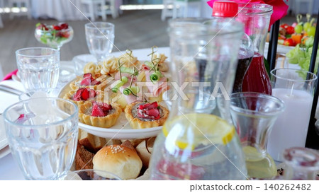Elegantly set banquet table displaying gourmet appetizers and sparkling drinks, highlighting sophisticated culinary presentation for festive gathering Elegantly set banquet table displaying gourmet appetizers and sparkling drinks, highlighting sophisticated culinary presentation for festive gathering 140262482