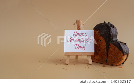 HAPPY VALENTINE'S DAY holiday greeting card Heart shaped dark chocolate croissant on beige background with copy space. Puff pastry new trendy sweet dessert bakery. Creamy dough HAPPY VALENTINE'S DAY holiday greeting card Heart shaped dark chocolate croissant on beige background with copy space. Puff pastry new trendy sweet dessert bakery. Creamy dough 140262517