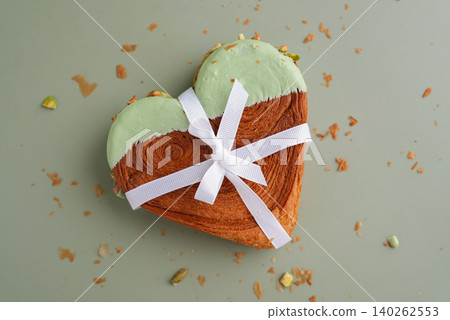 Present gift ribbon Delicious fresh croissant topped with Matcha Green Tea flavor Ganache. Creation unique heart shape bakery. Puff pastry holiday love symbol idea Valentine's day 140262553