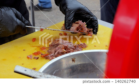 Meat slices prepared for serving, Chef organizes sliced roast meat for quick display at outdoor event, Workers carefully stack and position meat slices on trays for immediate serving at bustling Meat slices prepared for serving, Chef organizes sliced roast meat for quick display at outdoor event, Workers carefully stack and position meat slices on trays for immediate serving at bustling 140262740