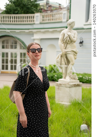 Woman in black polka dot dress stands in courtyard of Yeltsin Center Moscow branch, with classical sculpture and historic architecture. Cultural tourism, heritage, urban travel Woman in black polka dot dress stands in courtyard of Yeltsin Center Moscow branch, with classical sculpture and historic architecture. Cultural tourism, heritage, urban travel 140263070