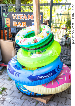 Colorful inflatable pool rings stacked near a vitamin bar sign Colorful inflatable pool rings stacked near a vitamin bar sign 140263155