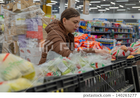 Woman Reading Salad Package Label In Supermarket, Brown Coat, Comparing Nutrition Facts And Ingredients, Leaning Over Display Bins, Careful Decision Making, Price Stickers And Barcode Visible, Woman Reading Salad Package Label In Supermarket, Brown Coat, Comparing Nutrition Facts And Ingredients, Leaning Over Display Bins, Careful Decision Making, Price Stickers And Barcode Visible, 140263277