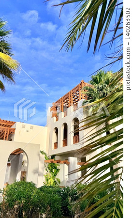 Architectural Elements With Lush Surroundings. Elegant Resort Exterior With Greenery And Shadows. Vibrant Plants Enclose Refined Structure Emphasizing Design And Contrast Architectural Elements With Lush Surroundings. Elegant Resort Exterior With Greenery And Shadows. Vibrant Plants Enclose Refined Structure Emphasizing Design And Contrast 140263502