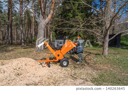 Man operating a wood chipper turning tree branches into mulch in Estonia, Northern Europe, mid Man operating a wood chipper turning tree branches into mulch in Estonia, Northern Europe, mid 140263645