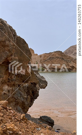Eroded Rocks In Tranquil Setting. Closeup Of Textured Rocks And Layered Geology. Detailed View Of Eroded Stone Formations And Mineral Deposits Near Calm Water Surface Eroded Rocks In Tranquil Setting. Closeup Of Textured Rocks And Layered Geology. Detailed View Of Eroded Stone Formations And Mineral Deposits Near Calm Water Surface 140263755