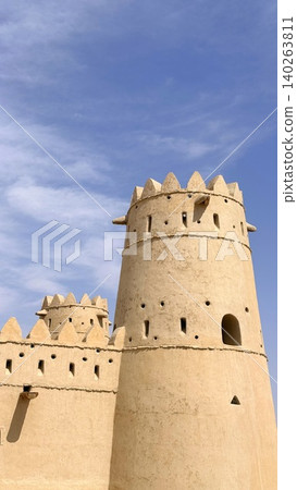 Vertical Perspective Of Sunlit Stone Lookout With Battlements. Sundrenched Cylindrical Fortress Featuring Narrow Openings And Protective Battlements Overlooking Landscape Vertical Perspective Of Sunlit Stone Lookout With Battlements. Sundrenched Cylindrical Fortress Featuring Narrow Openings And Protective Battlements Overlooking Landscape 140263811