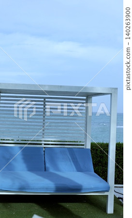 Serene Outdoor Setting. Charming Patio With Cushions. Relaxing Seating Area Beneath Cloudy Sky. Modern Outdoor Lounge With Lush Greenery And Comfortable Cushions 140263900