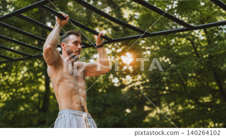Athletic Man Training on Monkey Bars in Park Athletic Man Training on Monkey Bars in Park 140264102