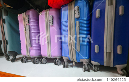Colorful hard-shell suitcases lined up against a wall, showcasing various sizes and designs, with wheels and zippers visible. Things for traveling. High quality photo 140264223