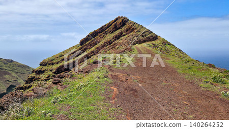 Scenic view of a winding dirt path leading up a green hillside overlooking the ocean in a coastal landscape. Northern viewpoint of La Palma Island Cruz de La Centinela. High quality photo Scenic view of a winding dirt path leading up a green hillside overlooking the ocean in a coastal landscape. Northern viewpoint of La Palma Island Cruz de La Centinela. High quality photo 140264252
