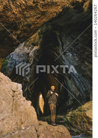 Man Explorer Standing on Cliff inside Cave Man Explorer Standing on Cliff inside Cave 140264267
