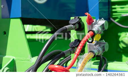 Close view of heavy duty electrical connectors, insulated cables, and terminal hardware mounted on green industrial equipment with metal fittings and bright workshop lighting Close view of heavy duty electrical connectors, insulated cables, and terminal hardware mounted on green industrial equipment with metal fittings and bright workshop lighting 140264361