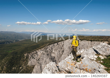 Man Tourist with Hiking Poles Walking in Mountains 140264387