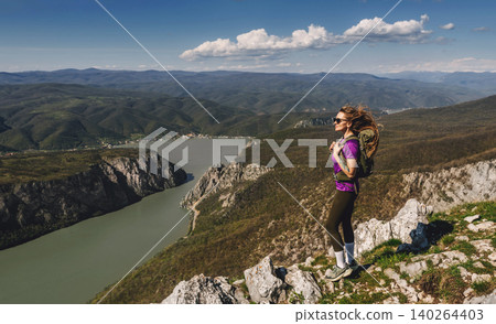 Female Explorer with Backpack Standing on Mountain Looking at Horizon Female Explorer with Backpack Standing on Mountain Looking at Horizon 140264403