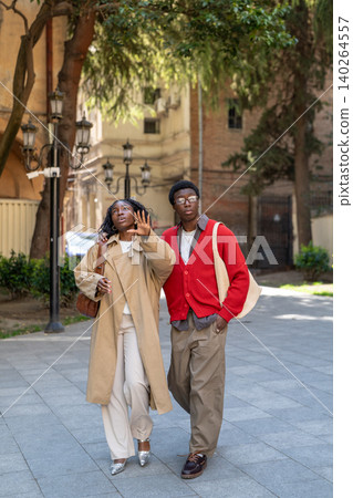 Fashionable curious african american man and woman spending weekend walking in city together Fashionable curious african american man and woman spending weekend walking in city together 140264557
