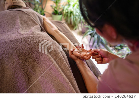 Cosmetologist in spa salon making relaxing gentle body massage for woman client lying on bed Cosmetologist in spa salon making relaxing gentle body massage for woman client lying on bed 140264627