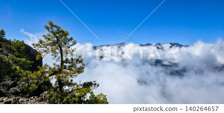 View of the peaks of the volcanic mountain range of the Caldera de Taburiente peeking out from behind the clouds from the side of Mount Pico Bejenado. High quality photo 140264657