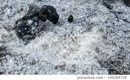 Close-up of salt crystals evaporated from ocean water against the background of black volcanic soil and stones. High quality photo 140264726