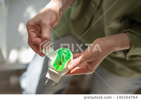 Woman using anti mosquito fumigator at home, electrical repellent device against insect problems Woman using anti mosquito fumigator at home, electrical repellent device against insect problems 140264764