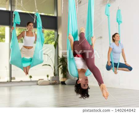 Athletic women hanging upside down in hammock. Fly yoga Athletic women hanging upside down in hammock. Fly yoga 140264842