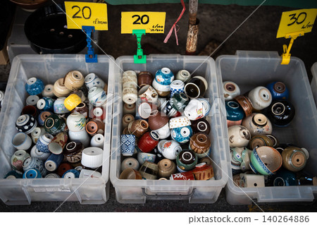 Containers filled with different cheap ceramic pots made from old used mugs selling at flower market Containers filled with different cheap ceramic pots made from old used mugs selling at flower market 140264886