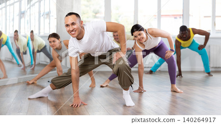 Happy young man and group of international dancers training before big performance in dance class Happy young man and group of international dancers training before big performance in dance class 140264917