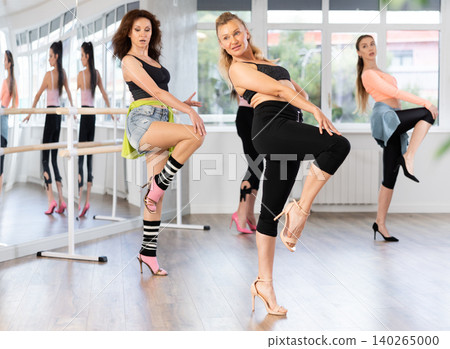 During lesson, woman learn to move and perform dance in heels with women companions During lesson, woman learn to move and perform dance in heels with women companions 140265000