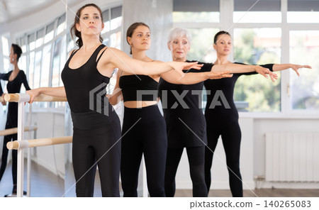 Group of people doing ballet exercises using barre in studio 140265083