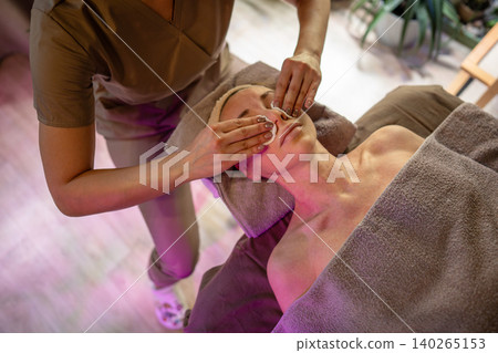 Lady dermatologist performing luxury skin care treatment procedure for woman patient on spa table. Lady dermatologist performing luxury skin care treatment procedure for woman patient on spa table. 140265153
