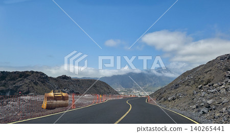 A new road laid through solidified lava flows after the eruption of the Tajogaite volcano on La Palma Island and ongoing repair and construction work and extraction of volcanic stones near the road 140265441