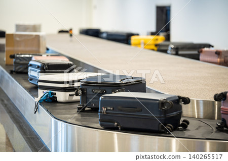Baggage delivery in airport. Conveyor belt with suitcases, bags and boxes spinning at terminal hall. Baggage delivery in airport. Conveyor belt with suitcases, bags and boxes spinning at terminal hall. 140265517