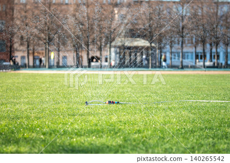 Special irrigation system evenly sprays water across fresh green lawn in park, seasonal landscaping. Special irrigation system evenly sprays water across fresh green lawn in park, seasonal landscaping. 140265542
