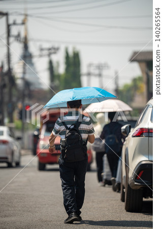 Man walking through city holding umbrella, health safety and protection from heatstroke in heatwave. Man walking through city holding umbrella, health safety and protection from heatstroke in heatwave. 140265564