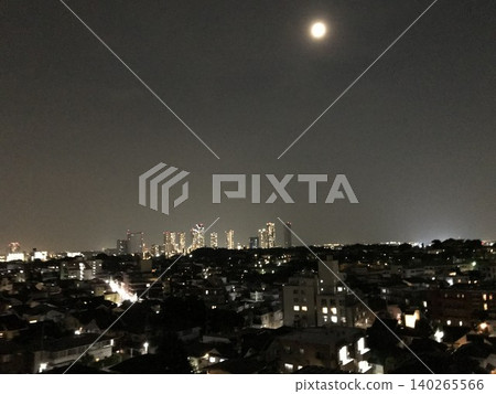 A full moon floating in the night sky and a night view of skyscrapers shining in the distance. A full moon floating in the night sky and a night view of skyscrapers shining in the distance. 140265566