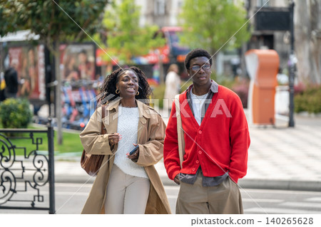 Happy carefree african american male and female people chatting and smiling walking down street. Happy carefree african american male and female people chatting and smiling walking down street. 140265628