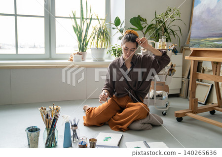 Calm woman painter getting inspiration while creating new masterpiece, immersed in thinking process. Calm woman painter getting inspiration while creating new masterpiece, immersed in thinking process. 140265636