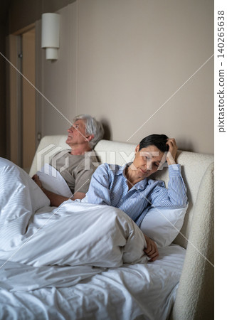 Disappointed senior woman turned away from frustrated husband while elderly couple sitting in bed. Disappointed senior woman turned away from frustrated husband while elderly couple sitting in bed. 140265638