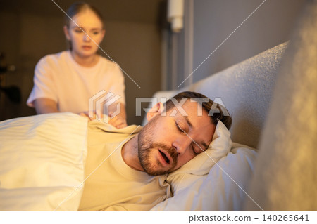 Frustrated woman trying to stop husband from snoring at night, pushing man on shoulder to wake up. Frustrated woman trying to stop husband from snoring at night, pushing man on shoulder to wake up. 140265641