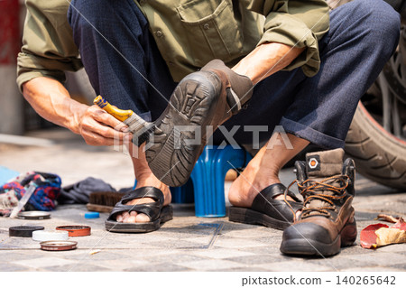 Local man cleaning shoes for locals and tourists, popular cheap street service in Hanoi, Vietnam. Local man cleaning shoes for locals and tourists, popular cheap street service in Hanoi, Vietnam. 140265642