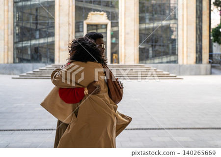 Fashionable African american man and woman friends meeting together at city street and hugging. Fashionable African american man and woman friends meeting together at city street and hugging. 140265669