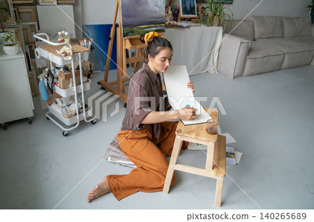 Creative working process at home gallery, thoughtful woman artist makes watercolor sketches in album Creative working process at home gallery, thoughtful woman artist makes watercolor sketches in album 140265689
