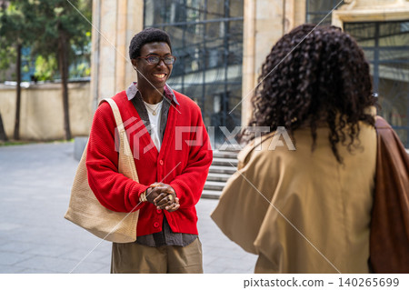 Positive african american man and woman couple students saying goodbye after meeting at street. 140265699