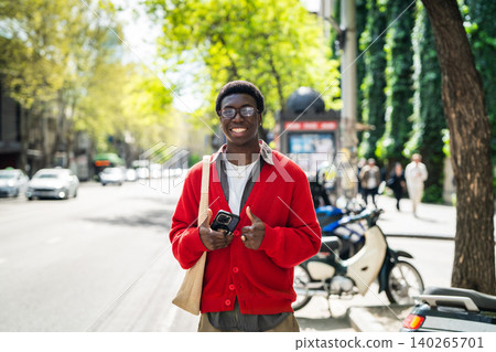 Cheerful black male with positive expression waiting for public transport and smiling at camera. Cheerful black male with positive expression waiting for public transport and smiling at camera. 140265701